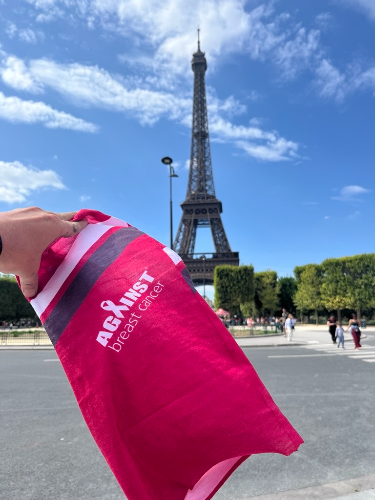 Austin holding his Against Breast Cancer-branded buff in front of the Eiffel Tower in Paris