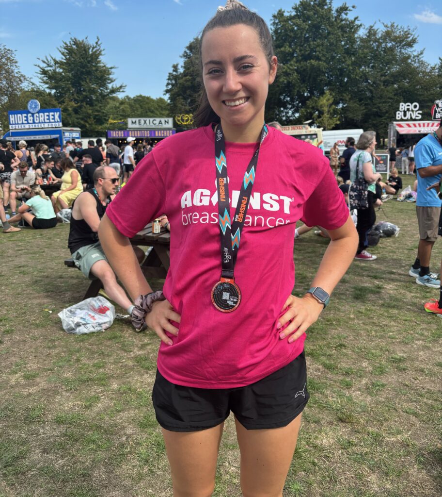 Maddy with her finisher's medal at the Big Half in London, wearing a pink Against Breast Cancer t-shirt.