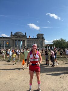 Kit in an ABC running vest and shorts with his medal standing in front of the Reichstag (German parliament building).