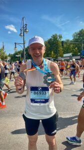 Mark holding both his Berlin Marathon finisher's medal and his six-star medal for completing all six marathon majors.