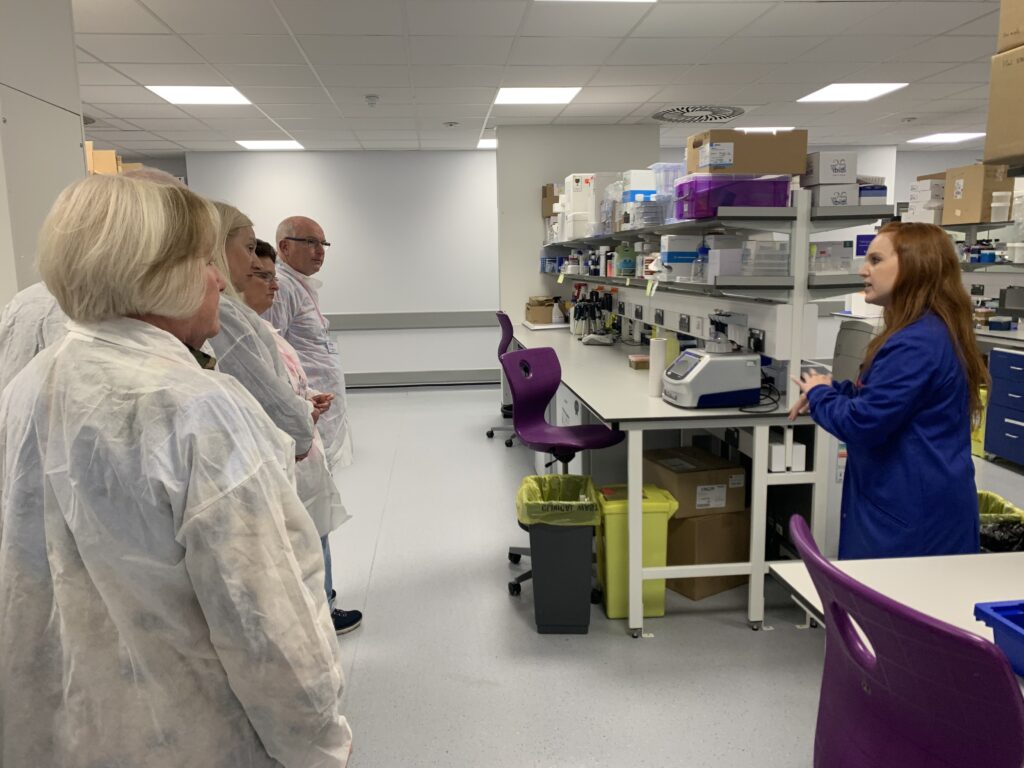 PhD student Grace Hayes (in a blue lab coat) giving a tour of the Against Breast Cancer labs during the open day at the University of Southampton