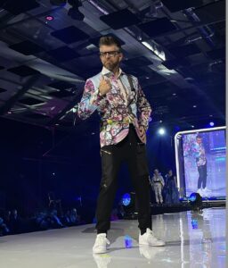 Phil modelling, wearing a colourful jacket, black trousers and white shoes.