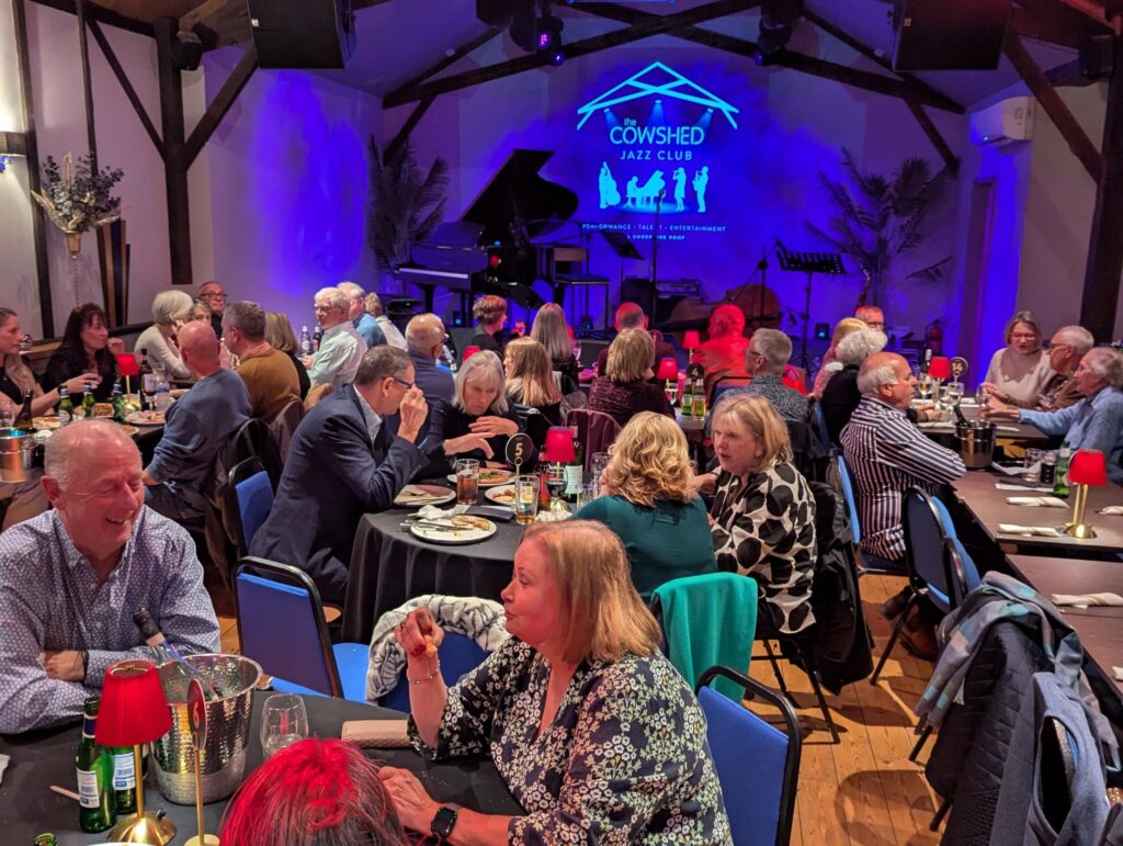 Attendees enjoying food and music at the Cowshed Jazz Club fundraising event for Against Breast Cancer
