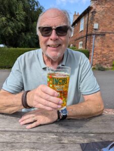 Mike on a bench holding a pint of cider.