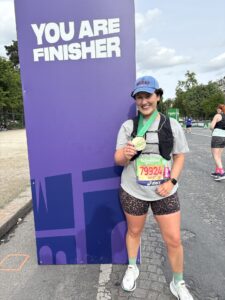 Katie Barr in front of a 'You Are Finisher' sign with her Paris medal
