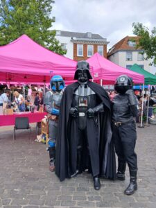 Jango Fett, Darth Vader and an Imperial TIE Fighter Pilot from UK Garrison stood in front of two pink gazeboes.