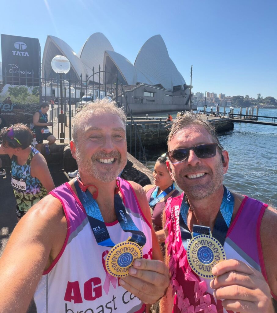 Glen and Martin with their Sydney Marathon medals standing in front of the Opera House.